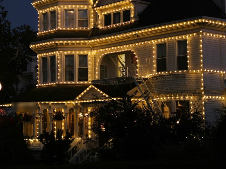 A Victorian building used as a restaurant, outlined in warm white bulbs along its rooflines, windows, and porch