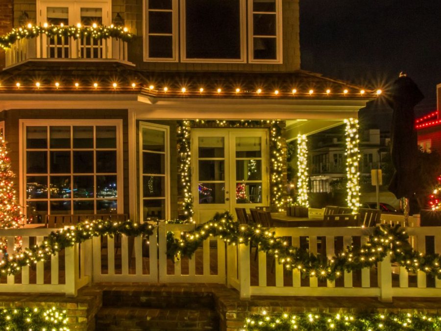 Lit garland draped along a picket fence and a balcony railing, with light-wrapped porch columns